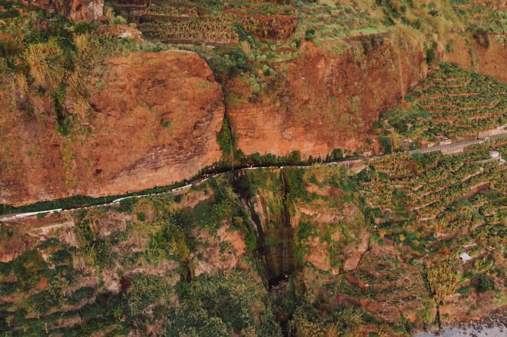 An aerial drone view of a waterfall over the road on Madeira