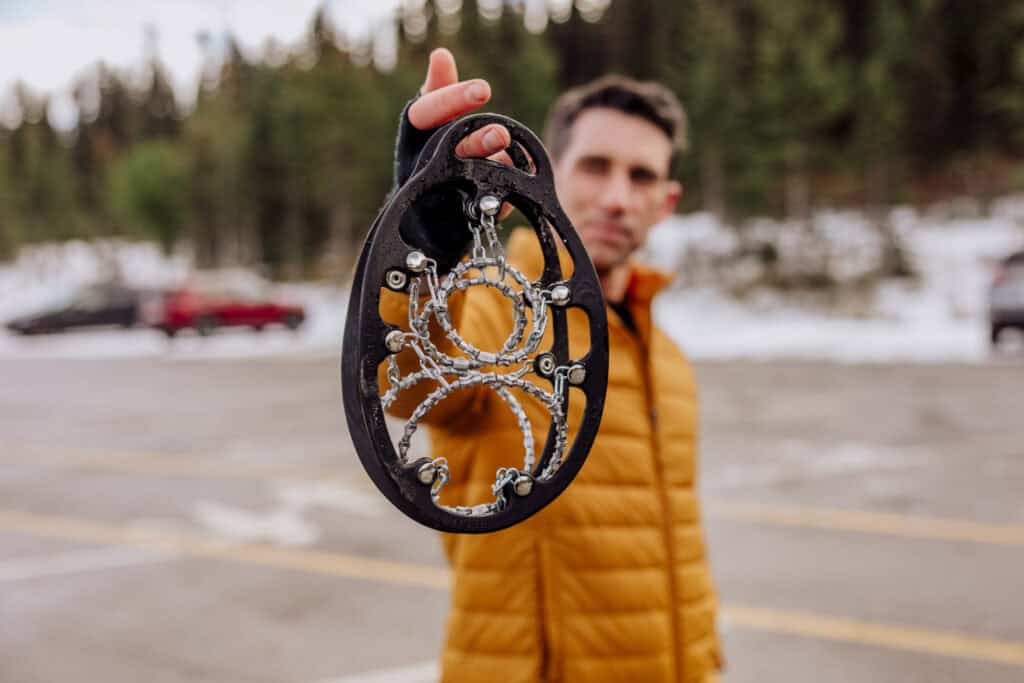 Jared Dillingham holding a pair of crampons or spikes for icy hiking trails