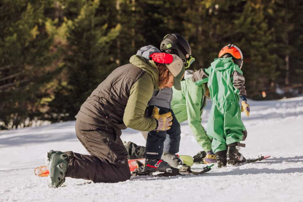 A dad helping kids get their skis on