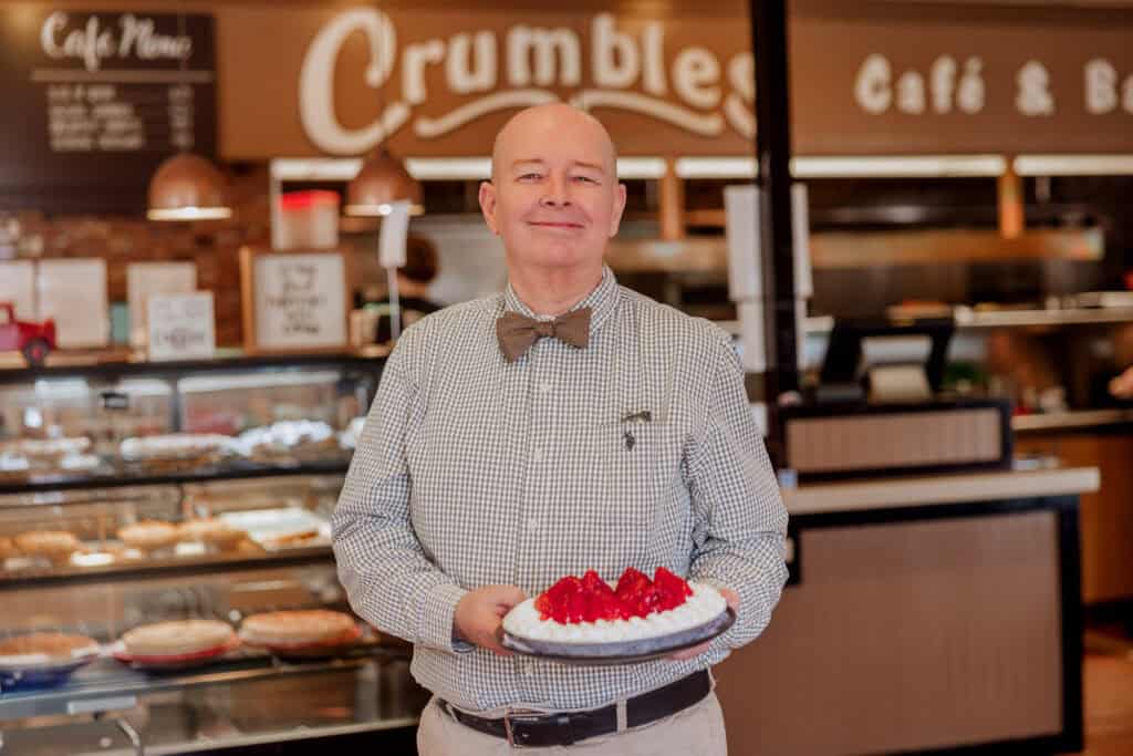 The manager holding a strawberry cheesecake at Crumbles Cafe and Bake Shop in Santa Maria, CA