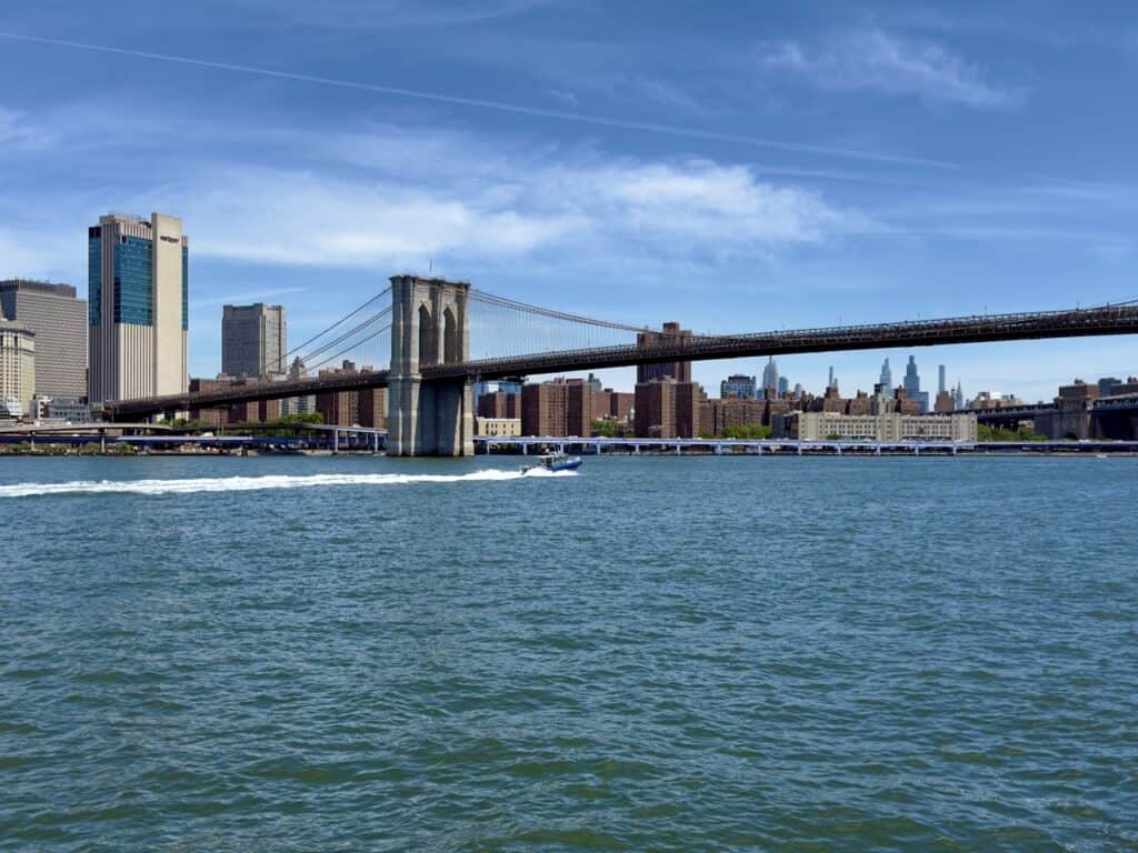 The Brooklyn Bridge on a sunny day with blue skies, looking toward Manhattan